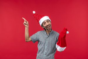 front view young man holding red christmas cap red wall